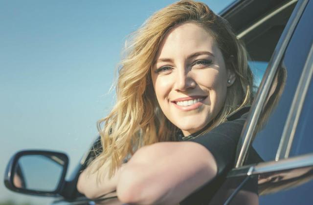 Freundliche Frau schaut aus PKW-Fenster